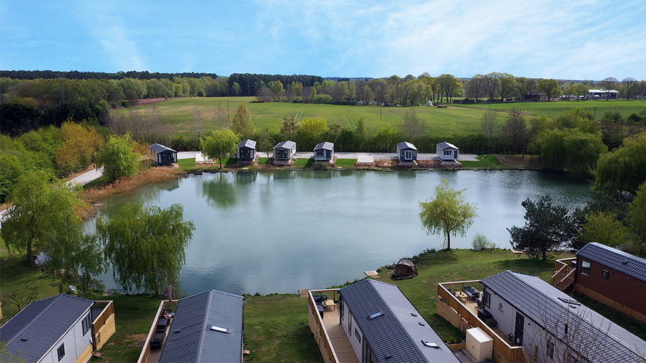 Aerial drone video with view of a holiday park with fishing lake and lodges in Teesside