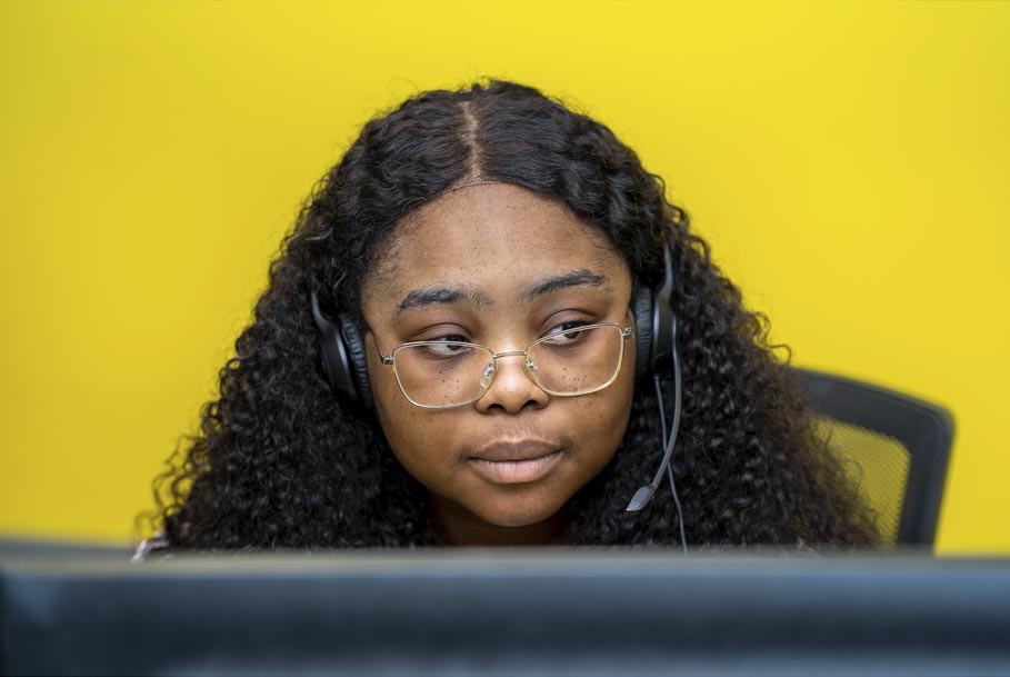 Authentic branding photography of staff member working at computer with yellow background in Teesside office