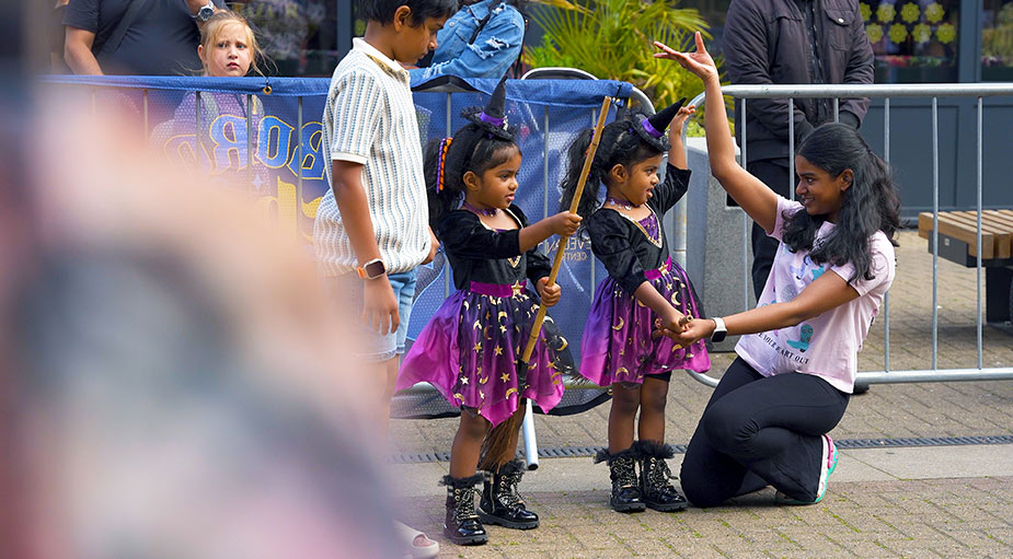 A charming portrait of twin girls dressed in matching witch costumes and hats at a seasonal family event in Captain Cook Square, Stockton-on-Tees area.