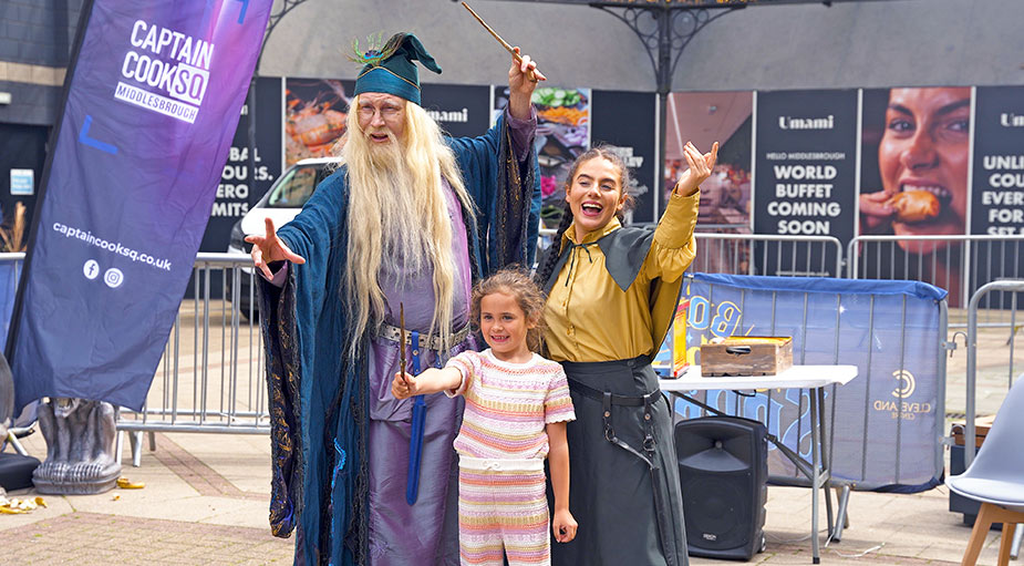 A clean, well-lit family portrait with a professional wizard character actor, captured for marketing use at a Middlesbrough public retail event.